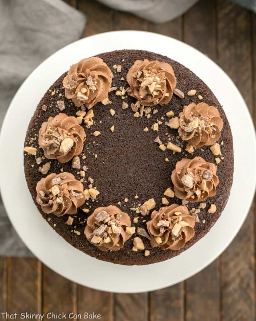 Triple Layer Chocolate Toffee Cake - 3 rich chocolate layers filled with chocolate buttercream and toffee bits Overhead view of aTriple Layer Chocolate Toffee Cake on a white cake stand