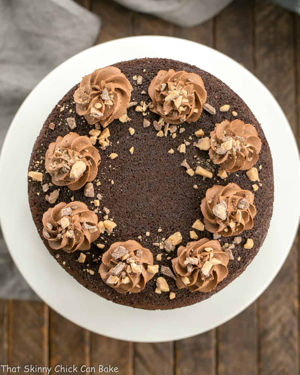 Overhead view of aTriple Layer Chocolate Toffee Cake on a white cake stand.