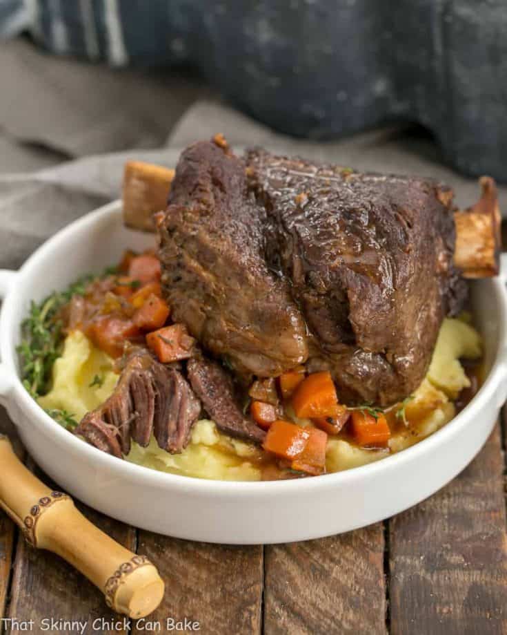 A plate of food, with Beef Short Ribs over potatoes