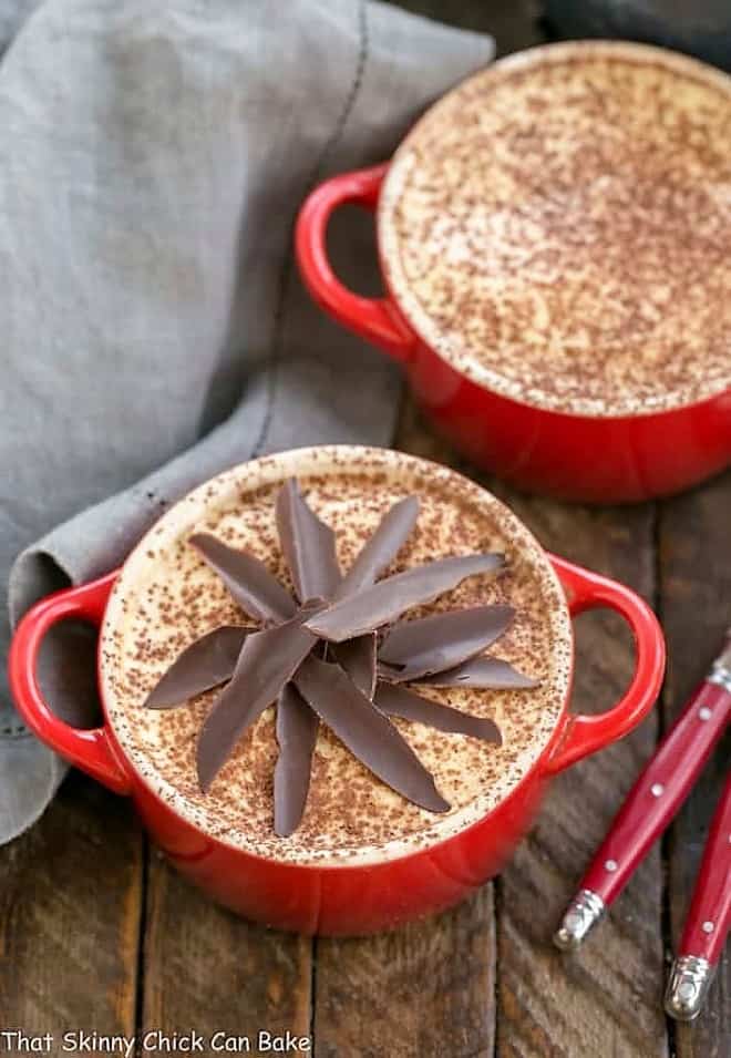 Kahlua Tiramisu for Two in red cocottes garnished with cocoa powder and chocolate shards.
