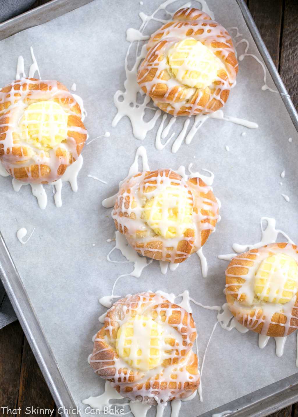 Cream Cheese Danish- tender, sweet yeast bread danish twists with a luscious cream cheese filling Danish Twists with Cream Cheese Filling on a parchment lined sheet pan.
