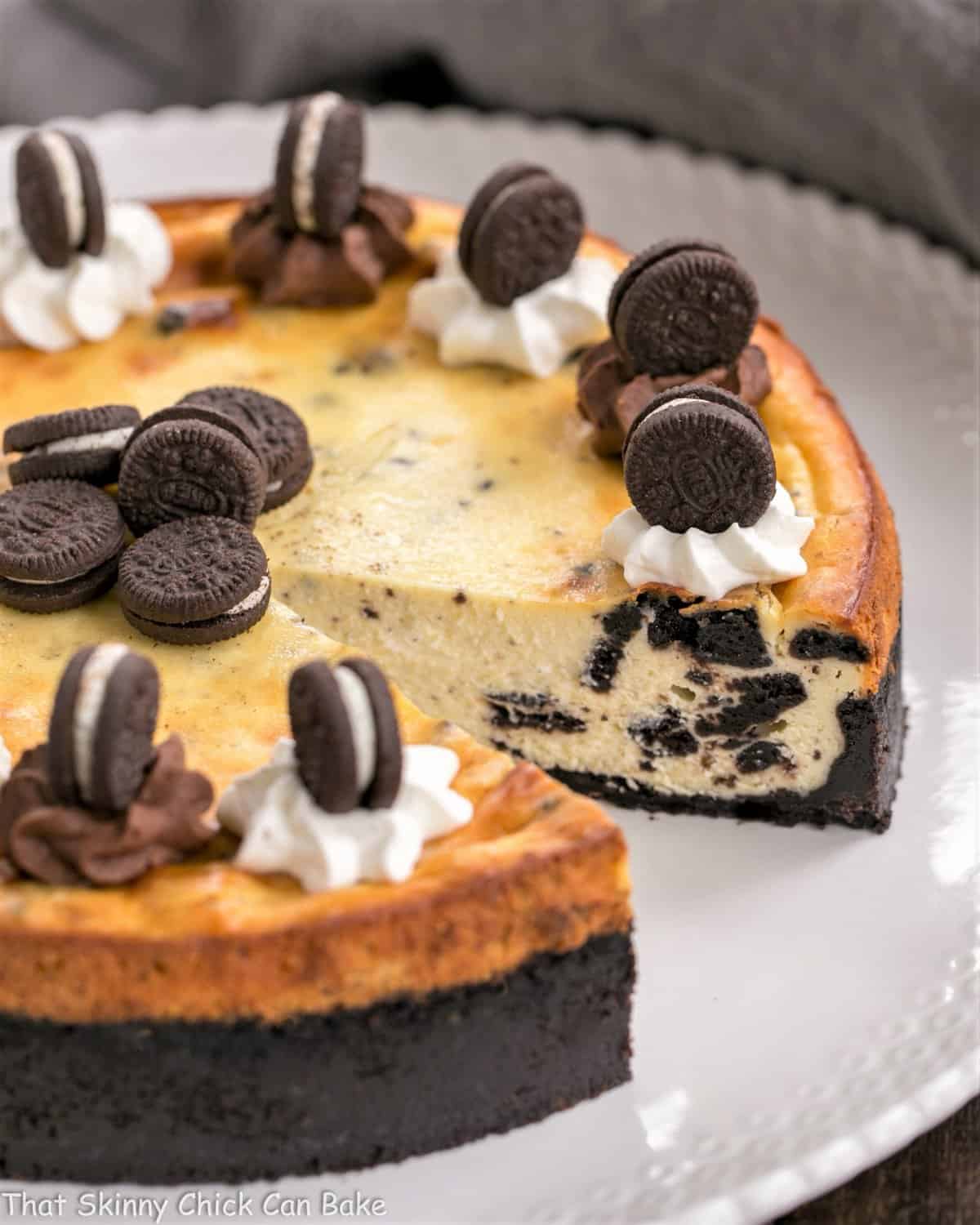 Oreo Cheesecake with Oreo Cookie Crust with slice gone on white serving plate.