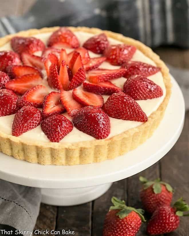 Strawberry Lemon Tart on a cake stand with fresh strawberries