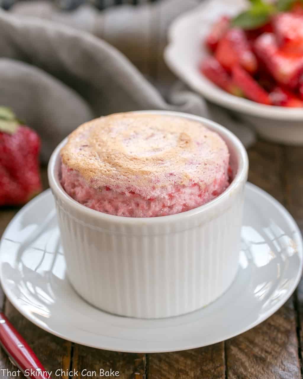 A baked strawberry souffle fresh out of the oven on a white plate.