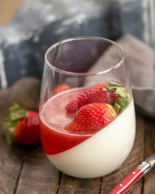 Vanilla Panna Cotta with Strawberry Gelée in a glass topped with fresh strawberries