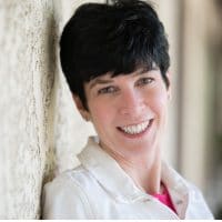 Liz berg profile photo leaning against a wall wearing a white jacket