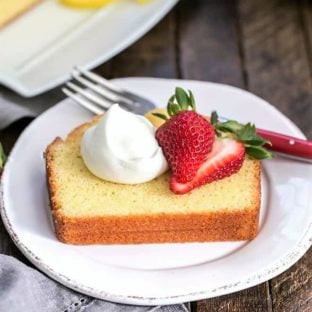 Glazed Lemon Pound Cake slice plated with berries and cream
