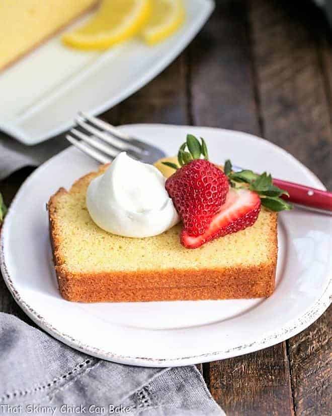 Glazed Lemon Pound Cake slice plated with berries and cream.