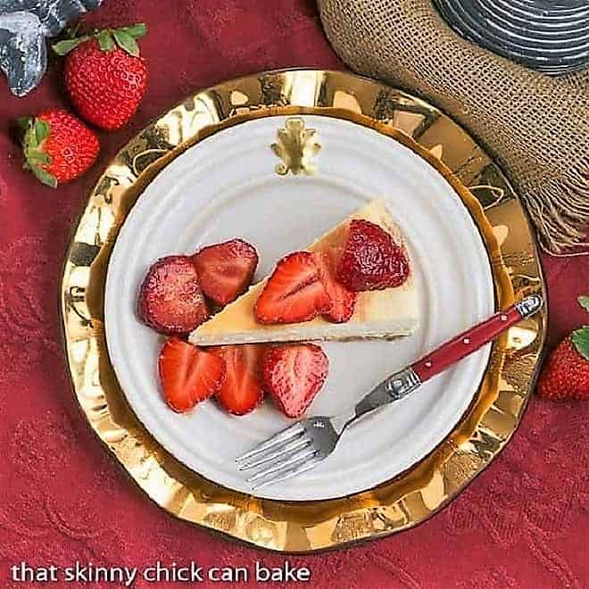 Italian Cheesecake with Balsamic Strawberries overhead view on a white plate over a gold charger plate.