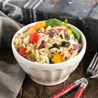 Orzo salad in a white bowl with 2 red handled forks