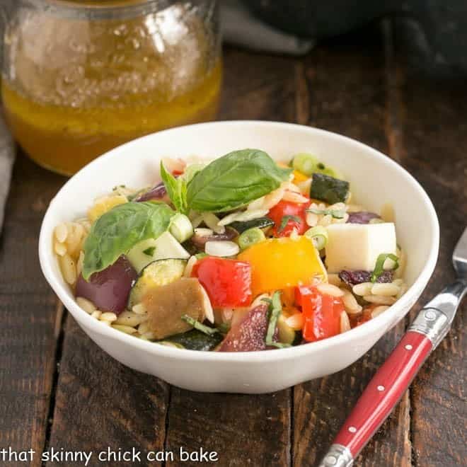 A small white bowl filled with orzo pasta salad.