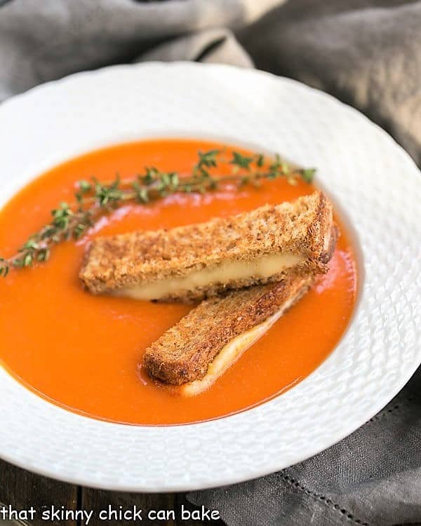 Thyme Kissed Tomato Soup in a white bowl with grilled cheese and thyme.