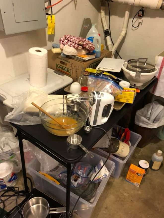 Makeshift basement kitchen with a card table, mixer, buckets of kitchen supplies