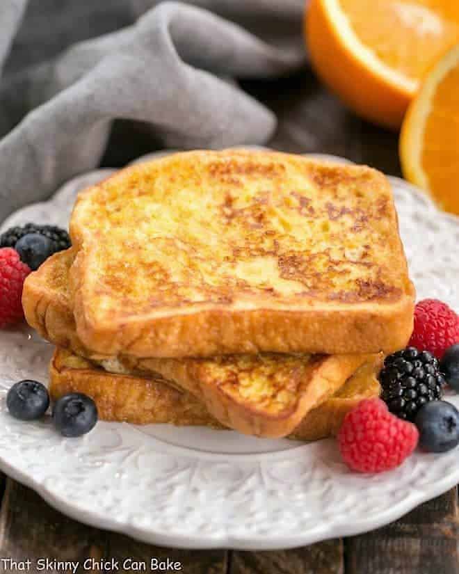 A stack of Grand Marnier French Toast on a white, decorative plate.