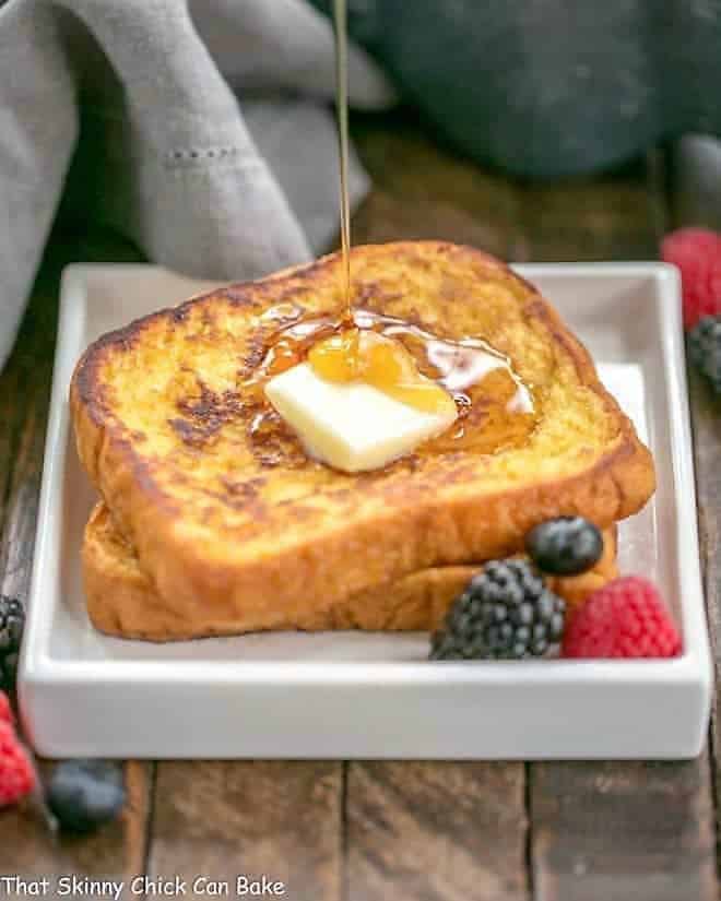 Grand Marnier French Toast on a square white plate with a stream of syrup pooling onto the surface.