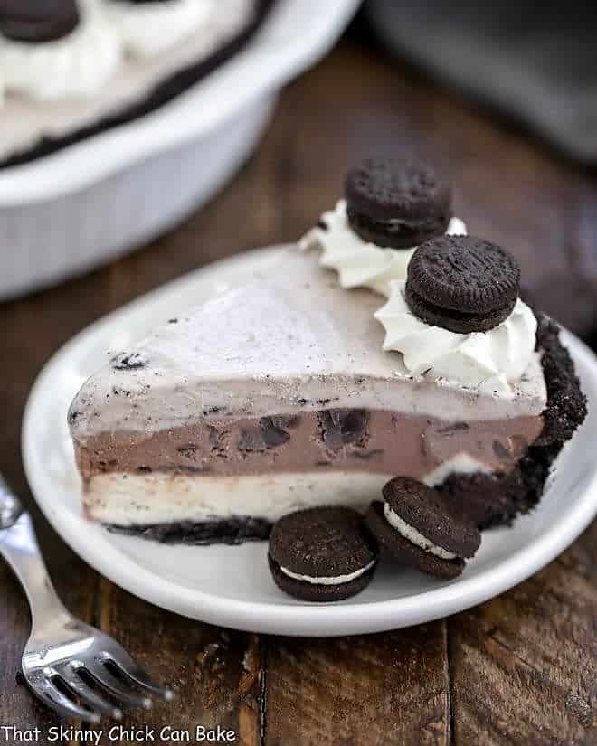 A slice of Layered Ice Cream Pie with Chocolate Cookie Crust on a white plate.