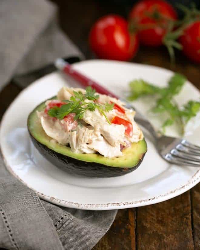 Southwestern Chicken Stuffed Avocado half on a white plate with a red handled fork