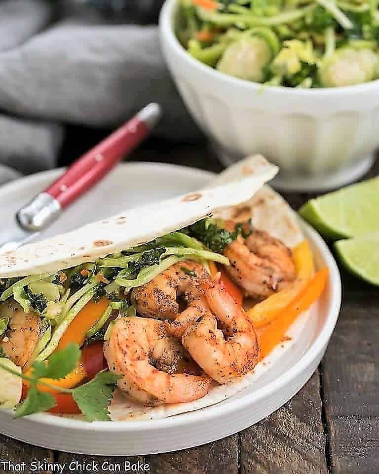Easy Seafood Fajitas on a white plate with a red handled fork.
