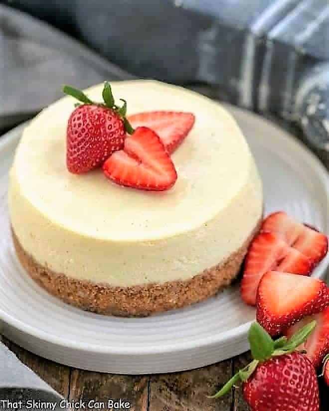 Vanilla Bean Instant Pot Cheesecake on a white serving plate garnished with strawberries