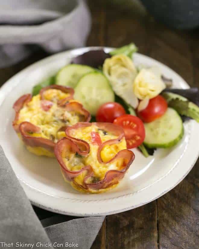Egg Muffins in Ham Cups with a green salad on a small white plate