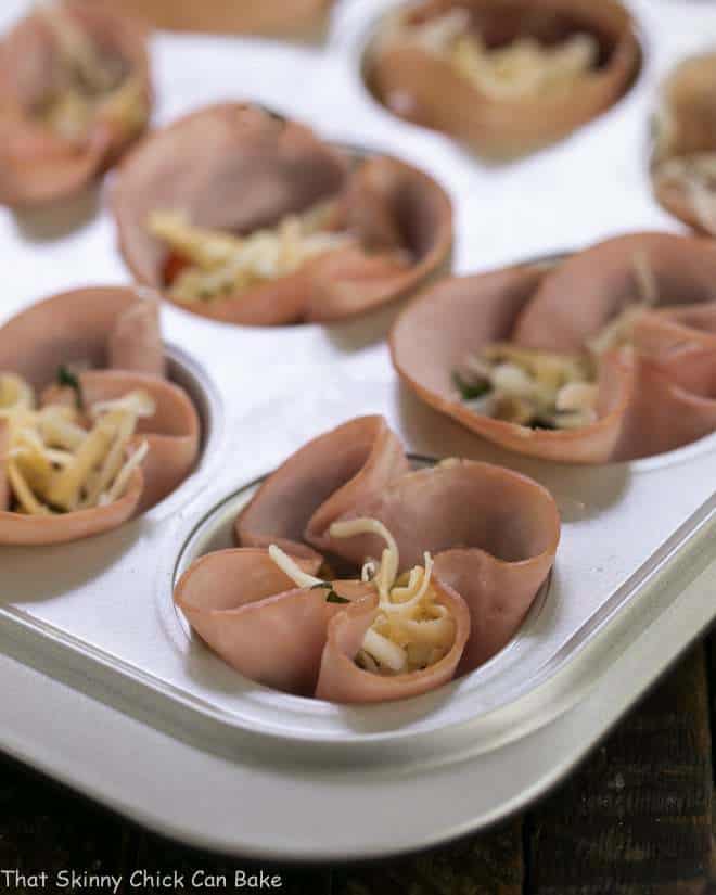 Egg Muffins in ham cups ready for the oven in a muffin tin.