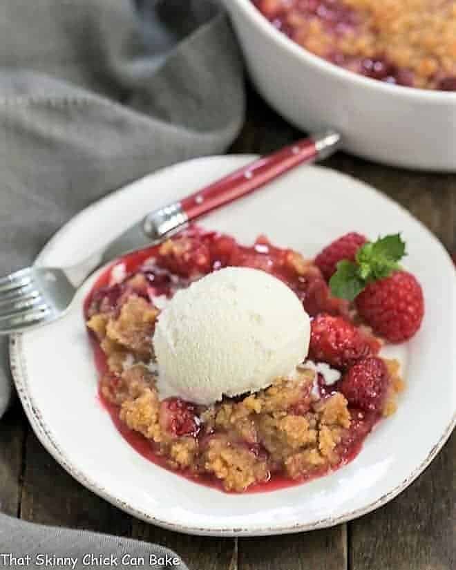 Fresh Raspberry Crisp - A super simple Raspberry Dessert that will knock your socks off! Overhead view of Fresh Raspberry Crisp on a white dessert plate with vanilla ice cream and fresh berries.