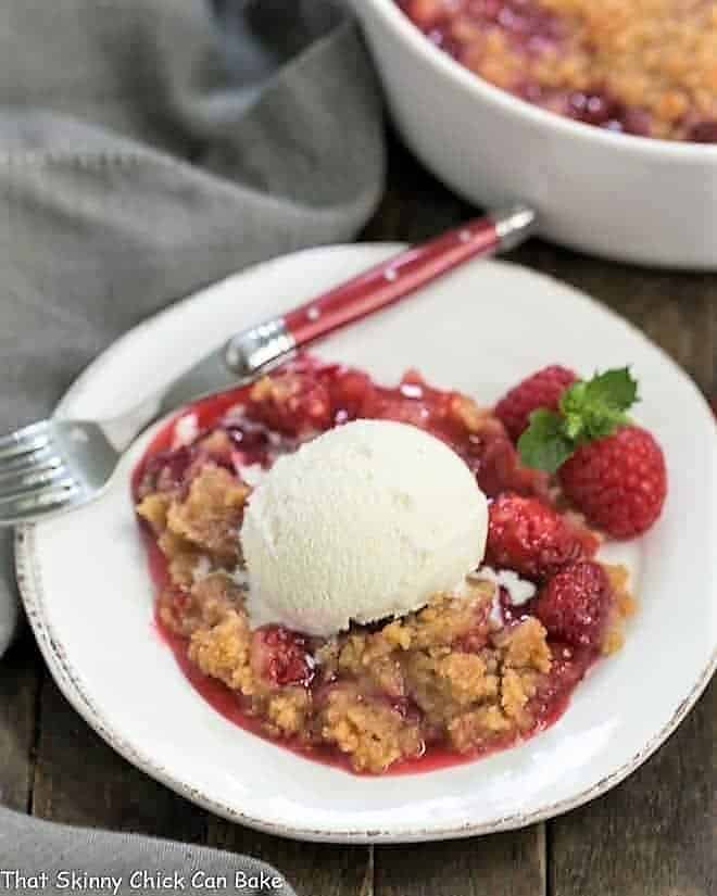 Overhead view of Fresh Raspberry Crisp on a white dessert plate with vanilla ice cream and fresh berries.