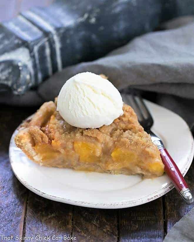 Slice of Easy Peach Crumb Pie topped with ice cream on a round white plate