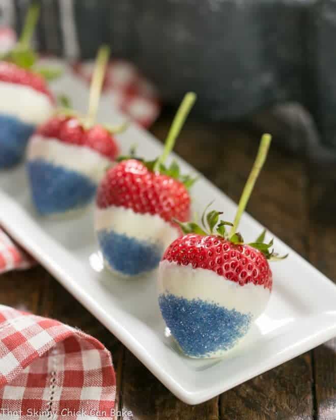 Red White and Blue Strawberries lined up on a narrow white ceramic tray