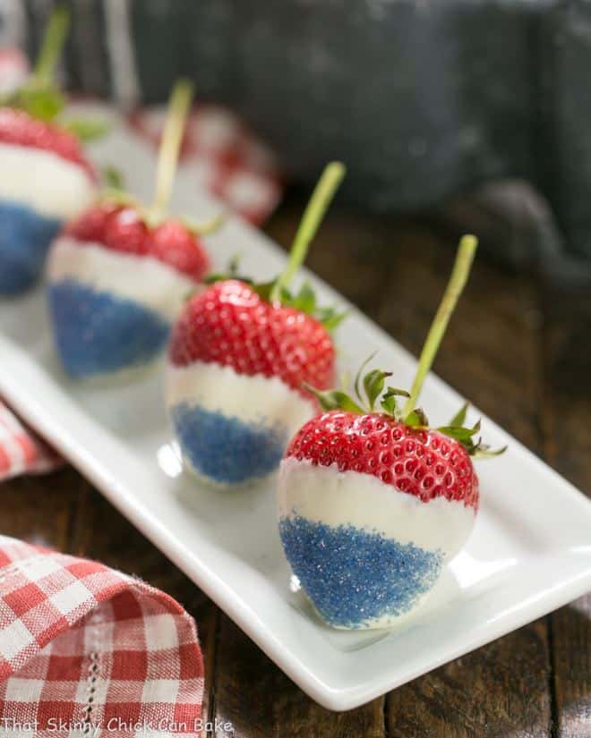 Red White and Blue Strawberries lined up on a narrow white ceramic tray.