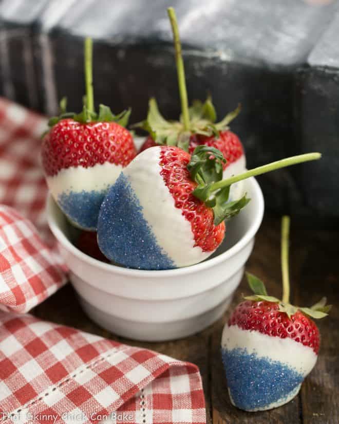 Red White and Blue Strawberries in a small white bowl with one next to the bowl.