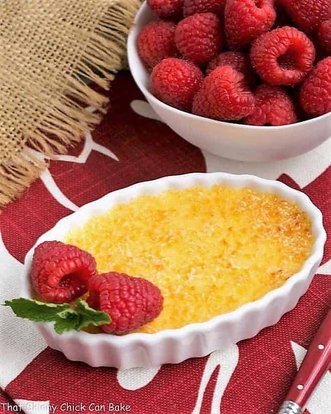 Classic Crème Brûlée in a white ramekin with a raspberry garnish.