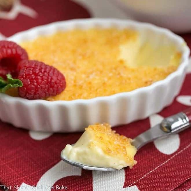 Classic Crème Brûlée with a spoonful removed and set in the foreground.