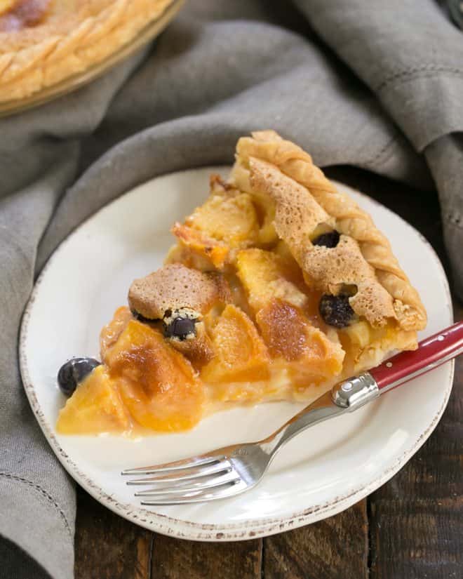 Blueberry Peach Custard Pie slice on a white dessert plate with a red handled fork