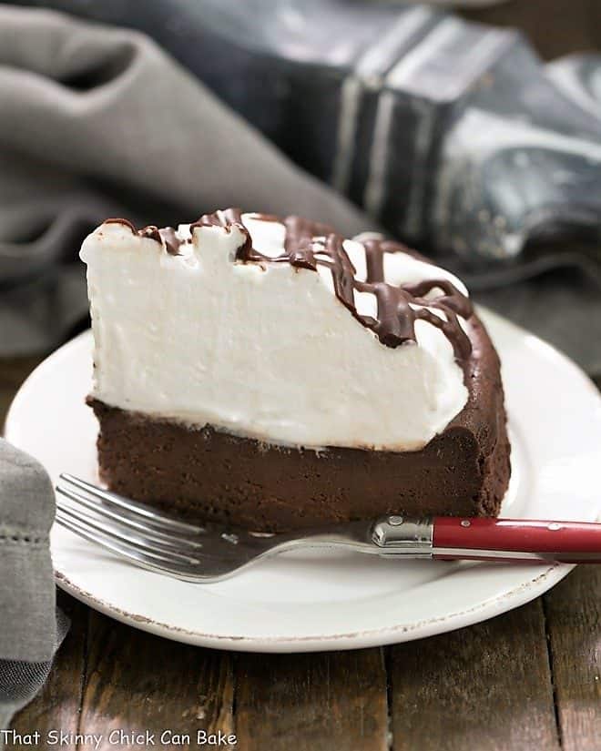 A slice of Flourless Chocolate Cake with Marshmallow Frosting on a white ceramic plate with a red handled fork