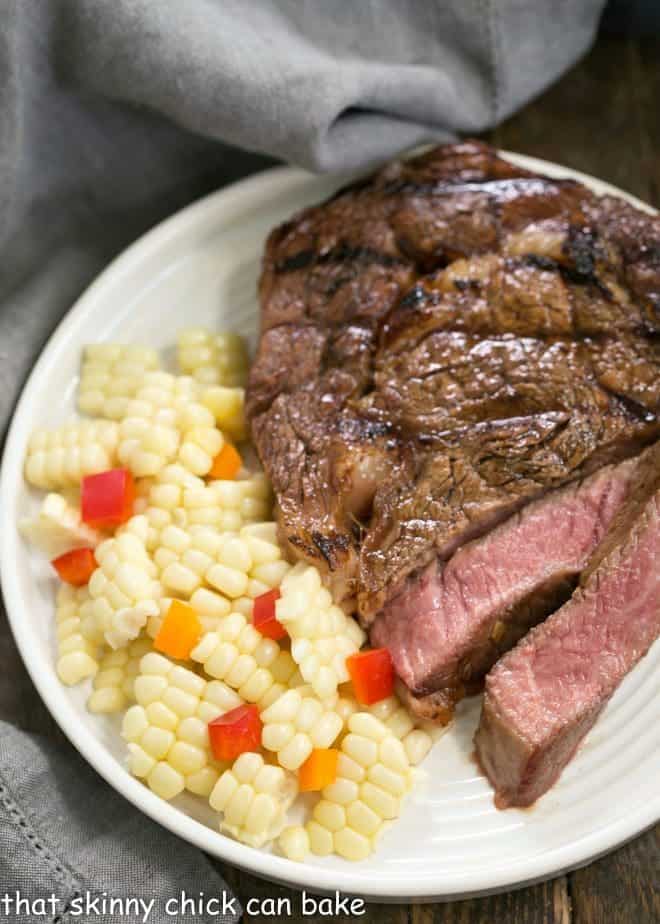 Grilled Korean Beef Steaks sliced on a white plate with corn