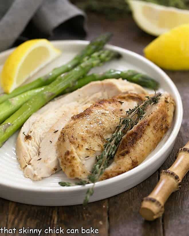 Instant Pot Rotisserie Chicken sliced with asparagus on a white dinner plate
