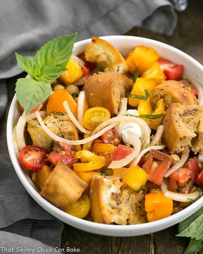 Summer Tomato and Burrata Panzanella Salad in a white serving bowl with a basil garnish.