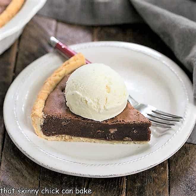 Fudgy Brownie Pie wedge topped with ice cream on a white dessert plate.