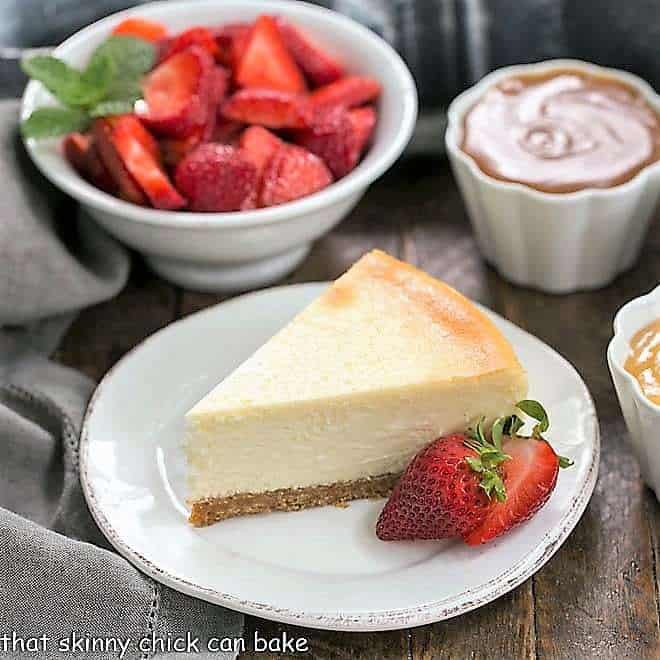 Perfect vanilla cheesecake with bowls of strawberries and toppings