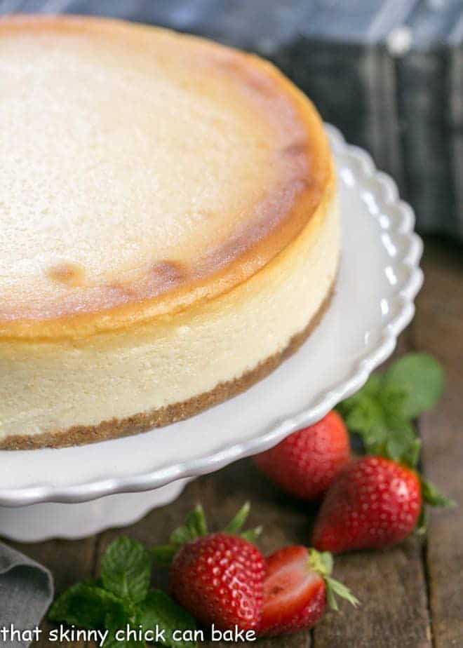 Perfect vanilla cheesecake on a white ceramic cake stand.
