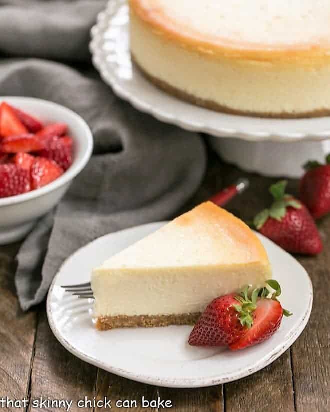 A slice of perfect vanilla cheesecake with a strawberry garnish