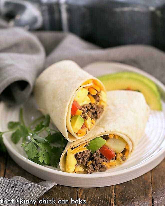 Tex-Mex Breakfast Burritos on a white plate with cilantro and avocados.