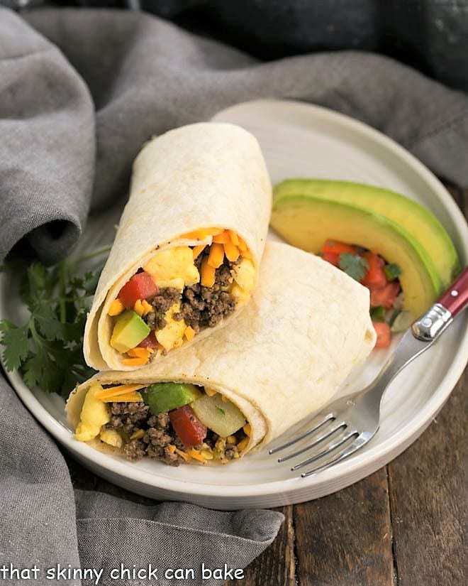 Tex-Mex Breakfast Burritos cut in half on a round white plate.