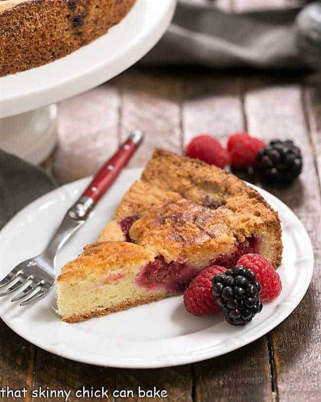 Mixed Berry Torte on a white plate with berries and a red handled fork.