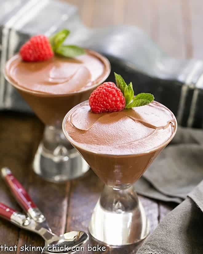 Two glasses of Chocolate Truffle Mousse topped with a raspberry and sprig of mint.
