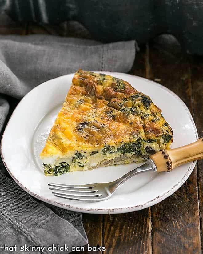 Slice of spinach quiche on a round white plate.