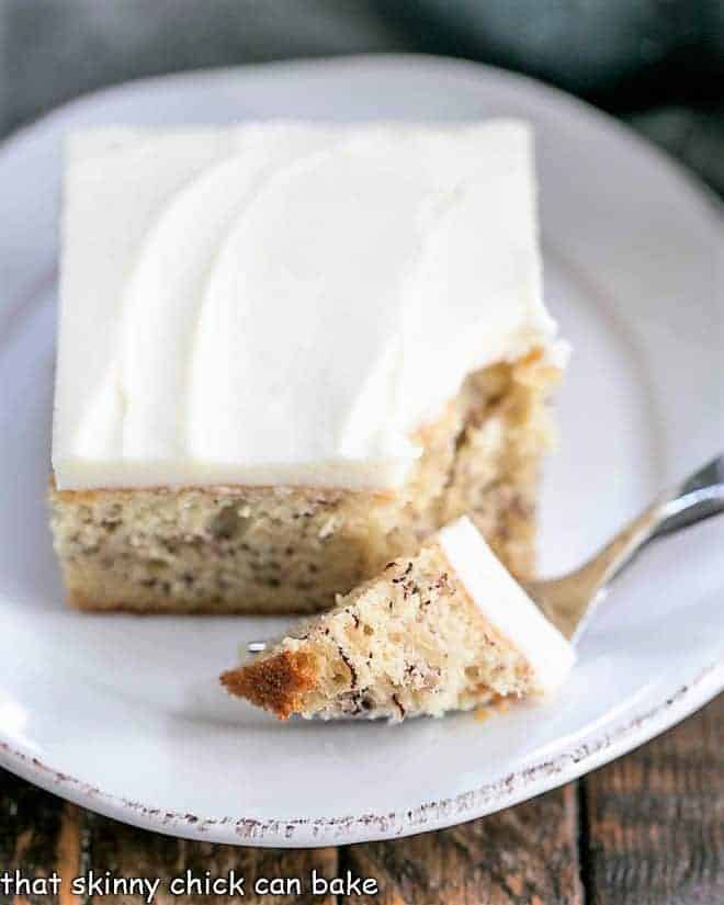 Bite of sour cream banana cake on a fork on a white plate.