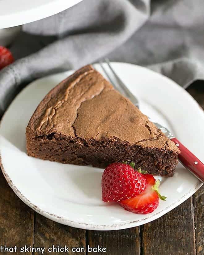 Italian Flourless Chocolate Cake on a white plate with strawberries.