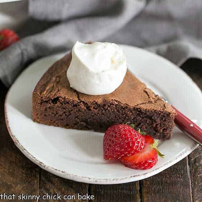 Italian Flourless Chocolate Cake with a dollop of cream, berries and a fork